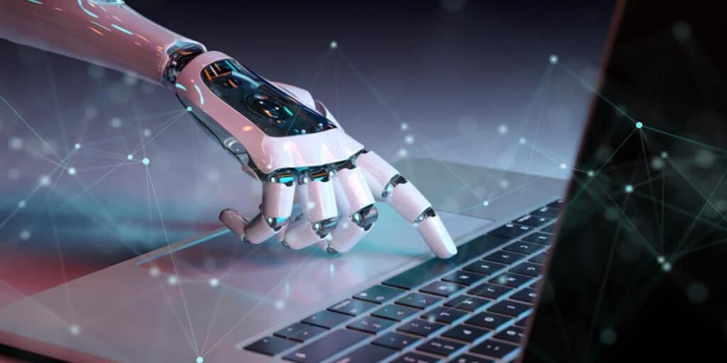 Une main automatisée devant un ordinateur symbolisant l’impact de l’IA dans l’automatisation des campagnes marketing